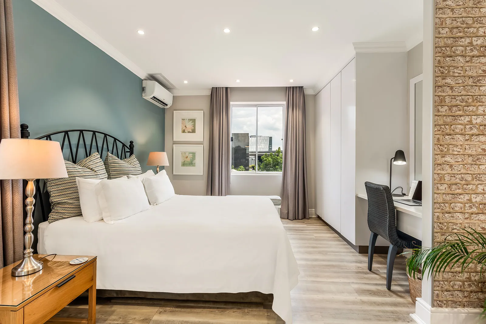 Bedroom with teal accent wall, work desk and brick detailing | Studio Stay on Sixty6 boutique hotel & accommodation in Sandton
